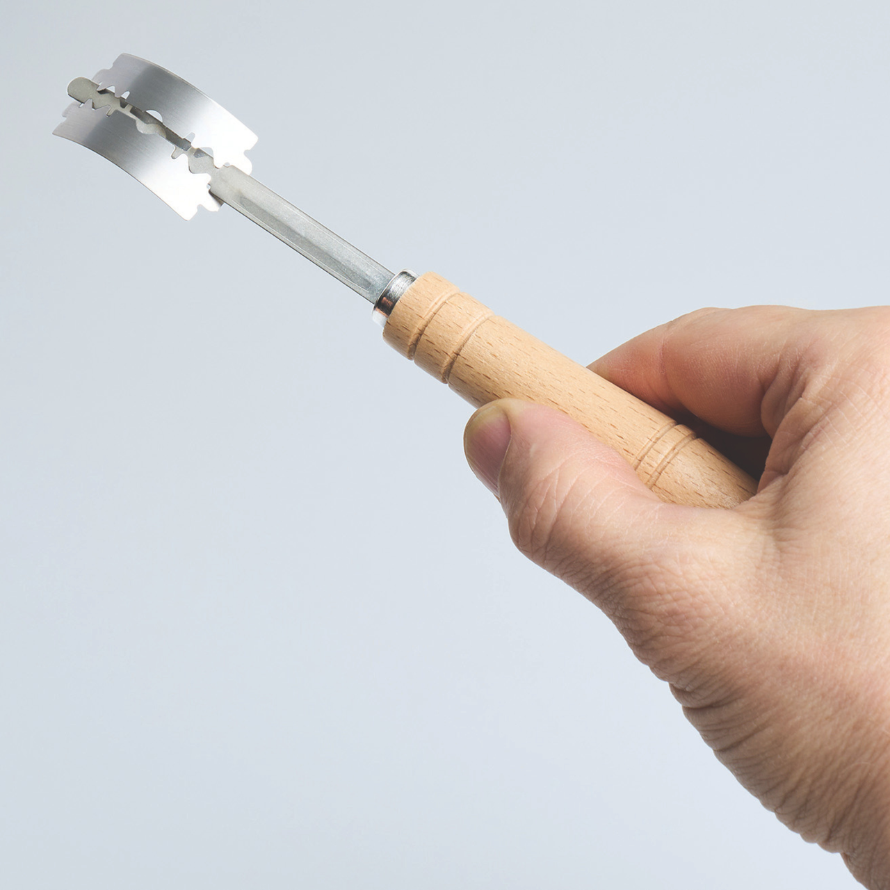 BakeMaster Dough Scoring Lame held in hand showing curved stainless steel blade