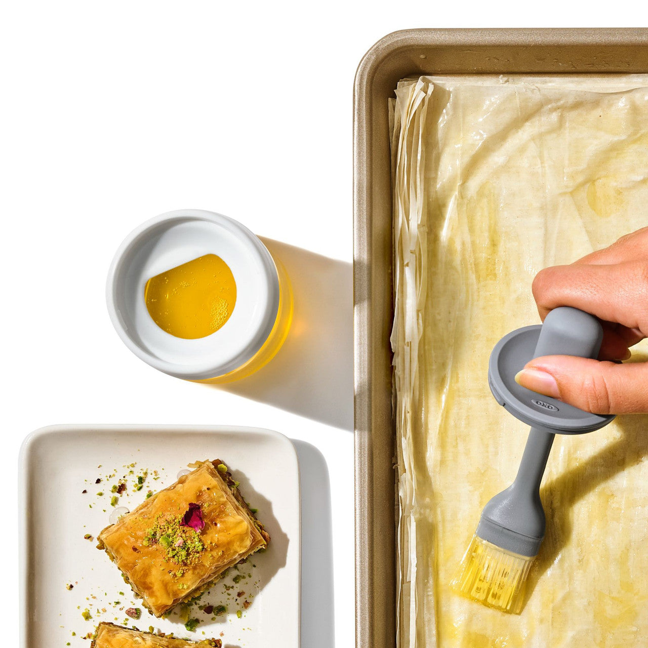 OXO cooktop brush detail view — silicone bristles and glass bottle